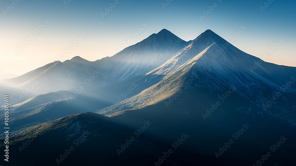Fototapeta premium Majestic mountain peaks with morning sun rays breaking through the clouds.