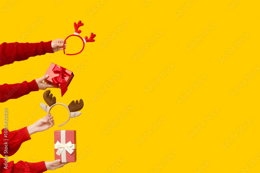 Female hands with Christmas reindeer horns headbands and gift boxes on yellow background Female hands with Christmas reindeer horns headbands and gift boxes on yellow background