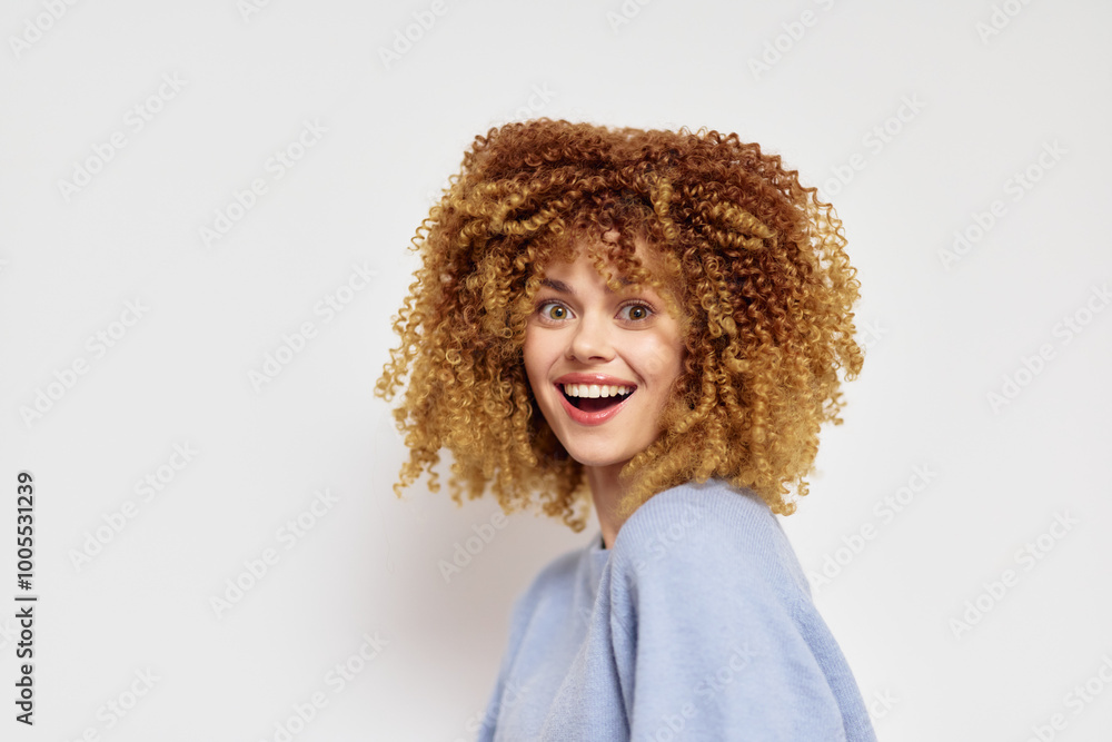 Smiling young woman with curly hair against a light background, showcasing joy and confidence in a cheerful pose Bright and lively expression enhances the mood Smiling young woman with curly hair against a light background, showcasing joy and confidence in a cheerful pose Bright and lively expression enhances the mood
