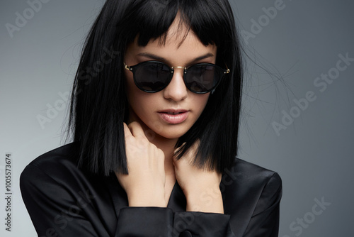 Wallpaper Mural Woman with black hair, wearing a black dress and shirt, with black sunglasses on and another pair atop her head, standing against a neutral background Torontodigital.ca