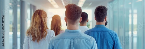 A group of young people walking together down a bright modern hallway, viewed from behind. Represents teamwork, collaboration, and togetherness.