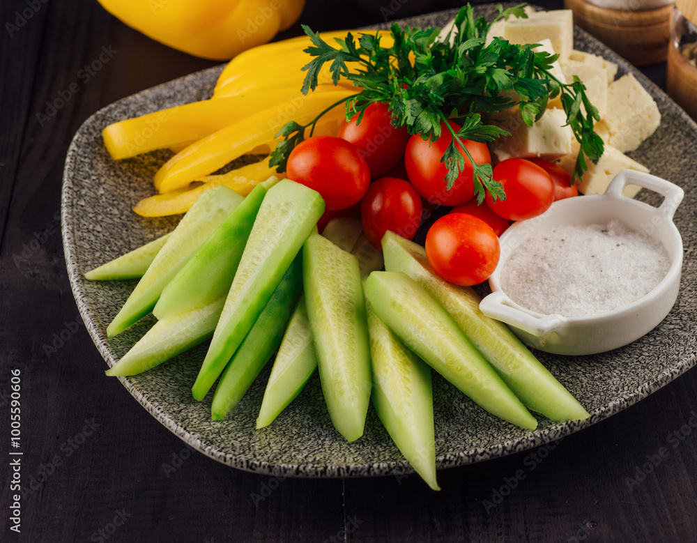Plate presenting sliced cucumbers, tomatoes, cheese and peppers with spices aside Plate presenting sliced cucumbers, tomatoes, cheese and peppers with spices aside