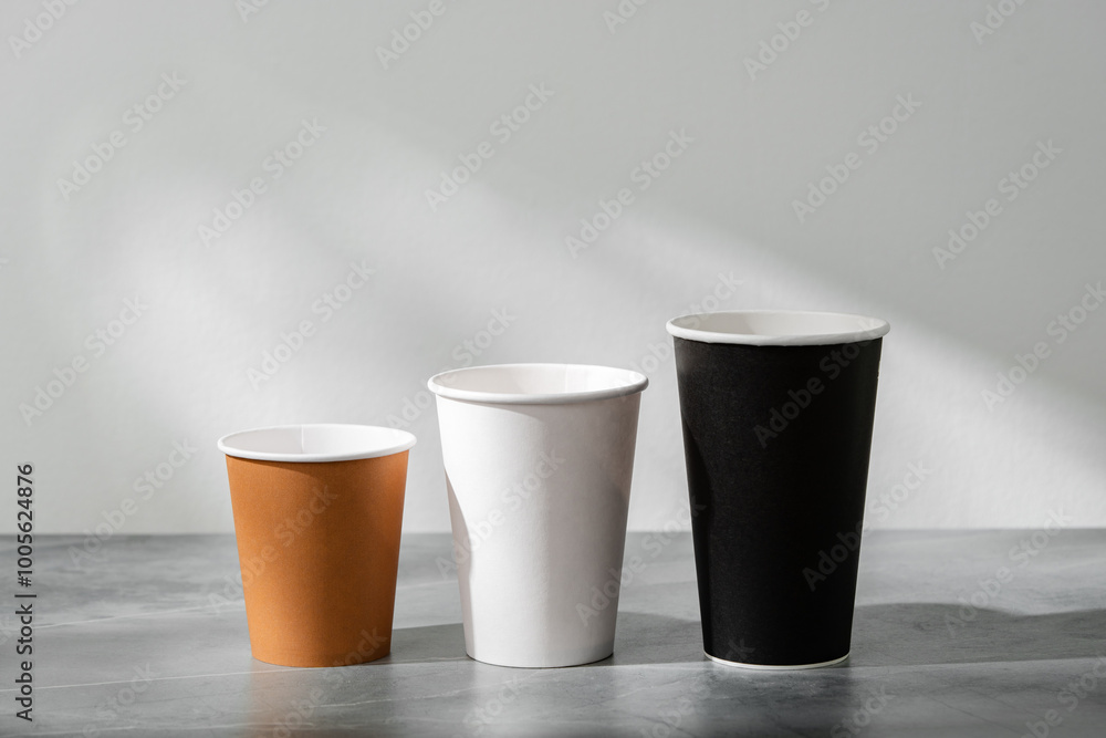 Stack of coffee cups in various colors with lids on a gray surface Stack of coffee cups in various colors with lids on a gray surface