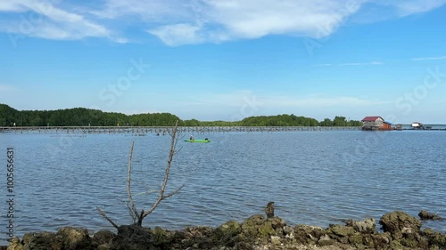 Bontang, East Kalimantan, Indonesia - September 27, 2024: The calm sea in the afternoon, a fisherman is netting fish on the edge of Galau beach. photo