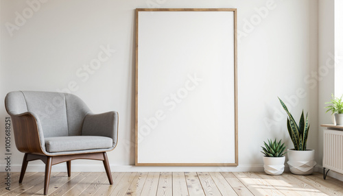 A minimalist living room with a gray armchair, wooden floor, and a white wall with a large blank canvas in a wooden frame. The room features a neutral color scheme, a snake plant in a white pot, and s