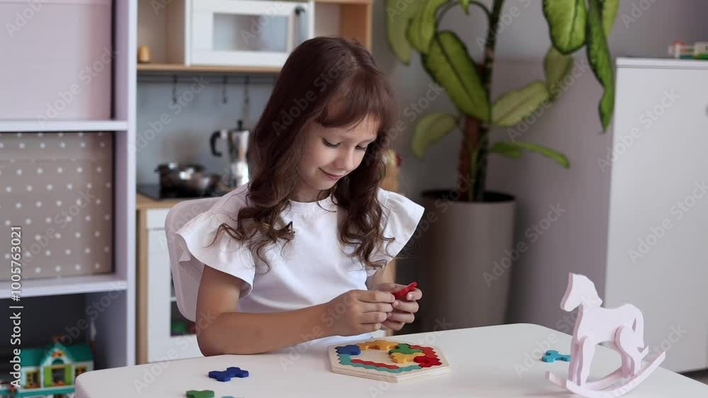 The kid girl is playing board educational game at the table in the children's room in slow motion. The concept of child development. The concept of leisure for children The kid girl is playing board educational game at the table in the children's room in slow motion. The concept of child development. The concept of leisure for children