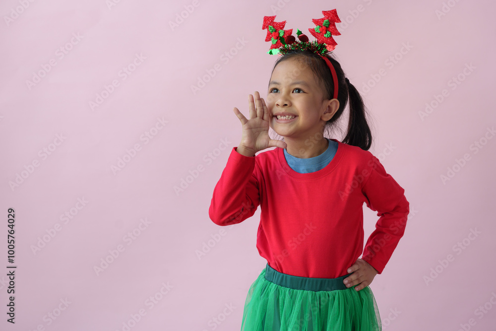 Adorable little Asian girl with Christmas tree headband, antlers showing various poses, standing, smiling, laughing, having fun in various poses, pink background. Holiday concept annual festival. Adorable little Asian girl with Christmas tree headband, antlers showing various poses, standing, smiling, laughing, having fun in various poses, pink background. Holiday concept annual festival.