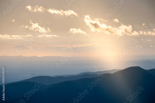 A serene view of sunlit mountains under a cloudy sky, beautifully capturing the layering of mountains and clouds as sunlight peeks through, creating a magical atmosphere in Montseny Spain photo