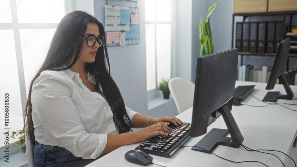 Young woman working at a computer in an office, wearing glasses and a white shirt, with a curvy physique. Young woman working at a computer in an office, wearing glasses and a white shirt, with a curvy physique.