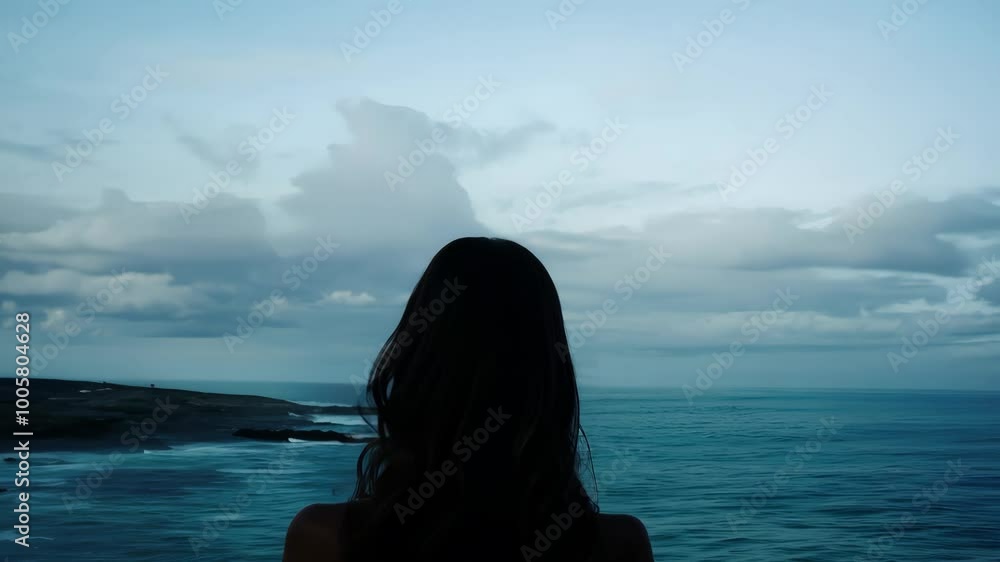 Silhouette of woman gazing at tranquil ocean and cloudy sky at dusk Silhouette of woman gazing at tranquil ocean and cloudy sky at dusk