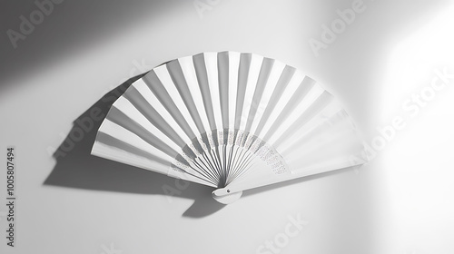 A white paper fan on a white background with a long shadow.