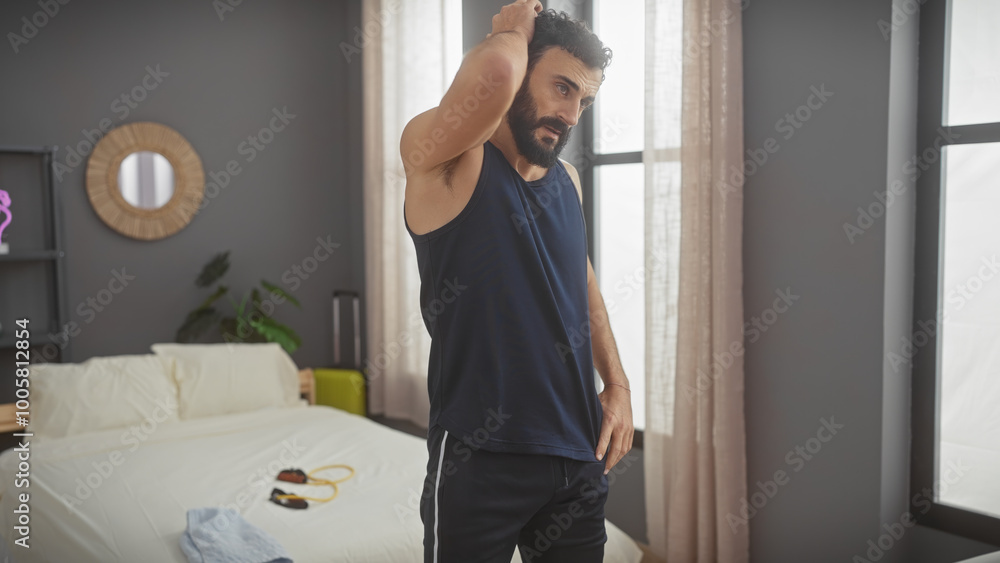 Bearded man stretching in a modern bedroom interior with natural light. Bearded man stretching in a modern bedroom interior with natural light.