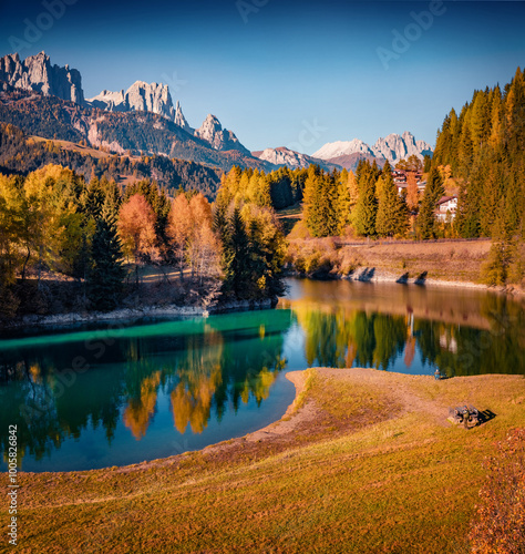 Colorful autumn view of Soraga lake. Beautiful morning cityscape of Soraga di Fassa village, Province of Trento, Italy, Europe. Great outdoor scene of Dolomite Alps. Traveling concept background.