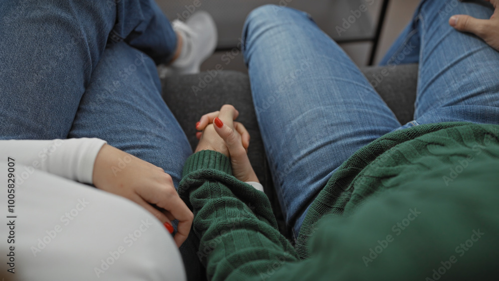Close-up of a man and woman holding hands in a cozy living room, symbolizing love and togetherness. Close-up of a man and woman holding hands in a cozy living room, symbolizing love and togetherness.