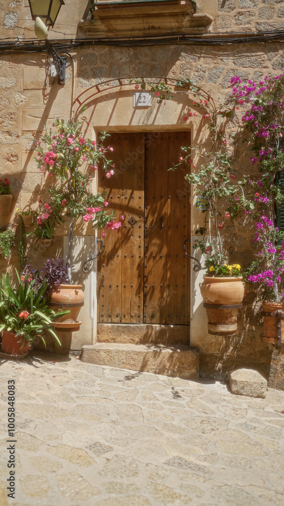 Obraz premium Charming mediterranean doorway in mallorca decorated with vibrant flowers and ancient stonework capturing the essence of spanish island life