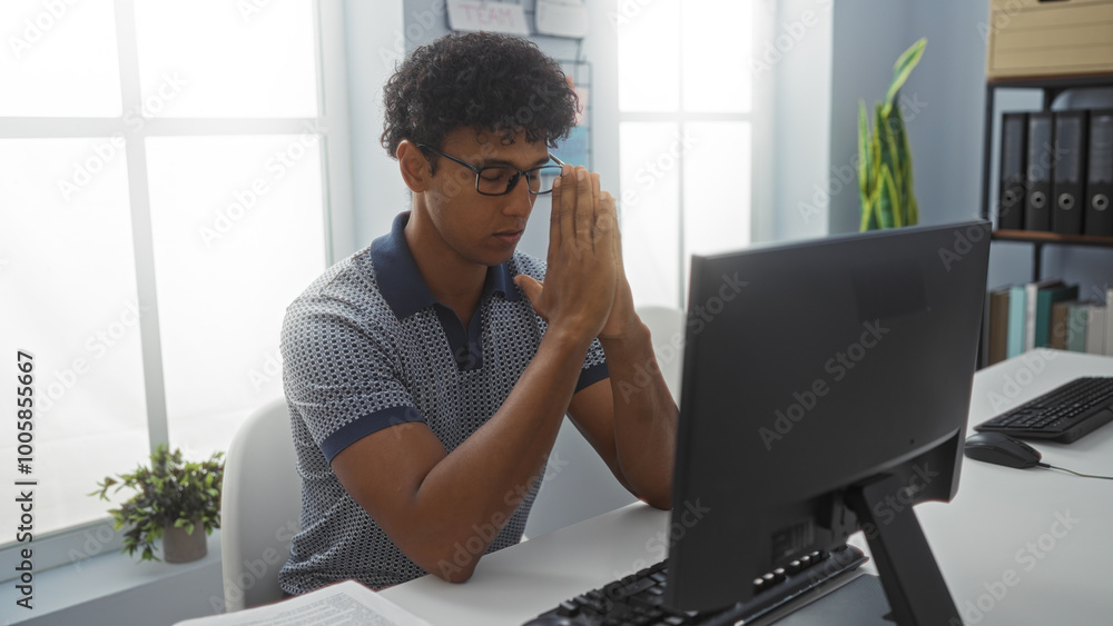 Young man working indoor office environment focusing on computer screen Young man working indoor office environment focusing on computer screen
