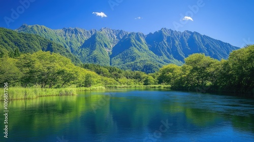 Vibrant green foliage along the banks of the Azusa River in Kamikachi, with the rugged Hotaka Mountains providing a stunning backdrop under a clear blue sky. photo