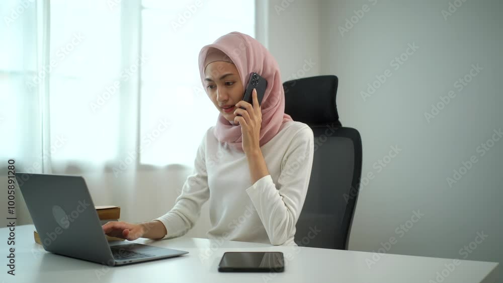 Young asian muslim business woman in hijab busy working on laptop while talking with mobile phone sitting at home office, beautiful female entrepreneur doing multi-tasking and communicating mobile.
Young asian muslim business woman in hijab busy working on laptop while talking with mobile phone sitting at home office, beautiful female entrepreneur doing multi-tasking and communicating mobile.