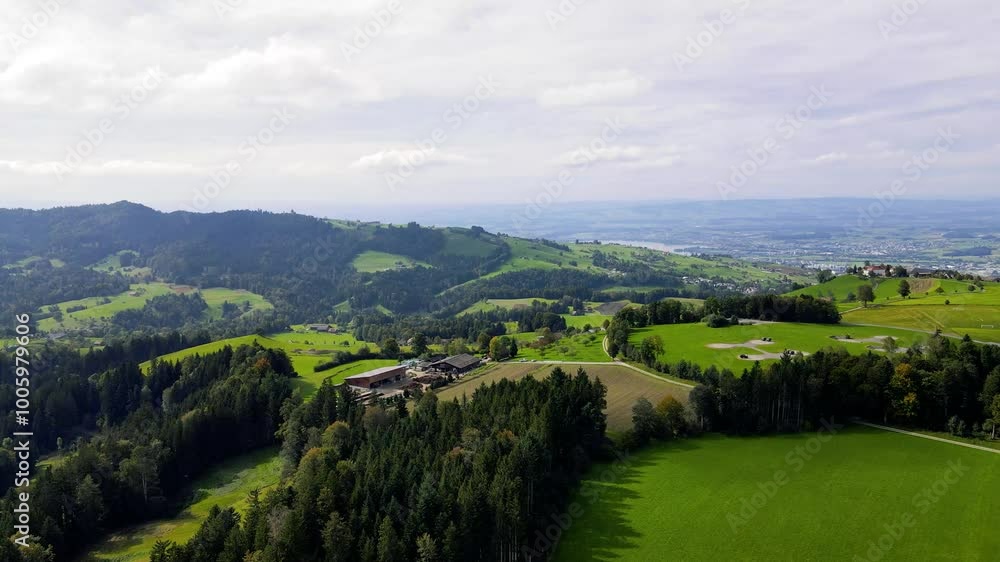 A panoramic view of the lush green countryside in Switzerland featuring Lake Zug in the distance beneath the rolling hills of Zugerberg Mountain