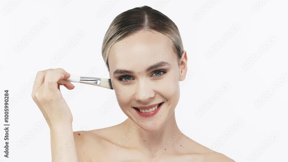 A young woman gently applies cream to her face with a brush. This tender touch emphasizes the importance of skincare and self-care, creating an atmosphere of relaxation and harmony. A young woman gently applies cream to her face with a brush. This tender touch emphasizes the importance of skincare and self-care, creating an atmosphere of relaxation and harmony.