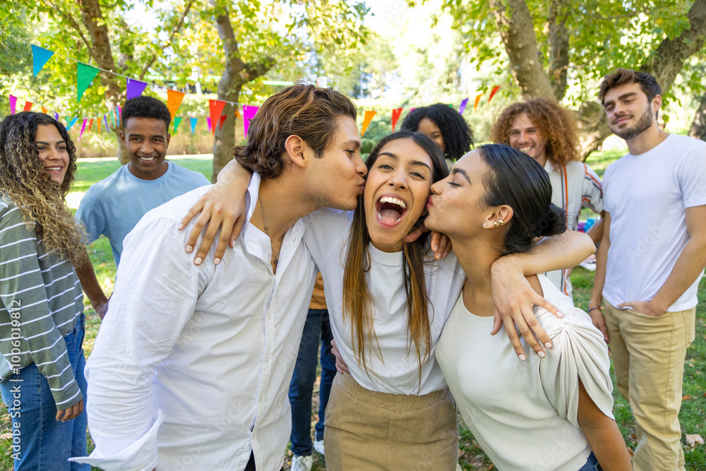 Two friends kissing happy girl on cheeks at park party Two friends kissing happy girl on cheeks at park party