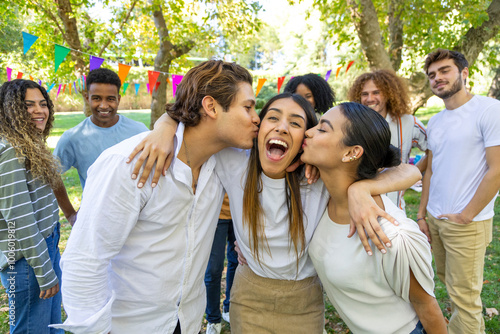 Two friends kissing happy girl on cheeks at park party