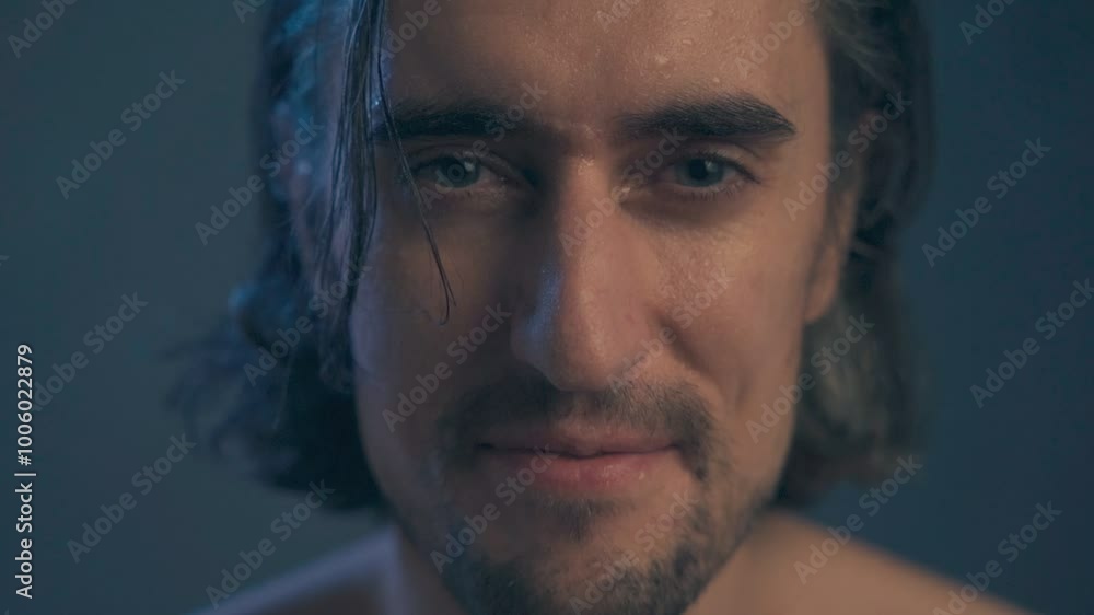 young handsome man without outerwear with long hair, brunette extra close up, large expressive eyes, looks in surprise into the frame, splashes of water fly on his face, closes his eyes, slow motion young handsome man without outerwear with long hair, brunette extra close up, large expressive eyes, looks in surprise into the frame, splashes of water fly on his face, closes his eyes, slow motion