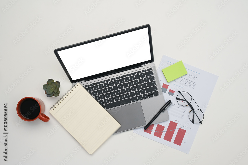 Top view of laptop with blank screen, notepad, financial document and coffee cup on white background Top view of laptop with blank screen, notepad, financial document and coffee cup on white background