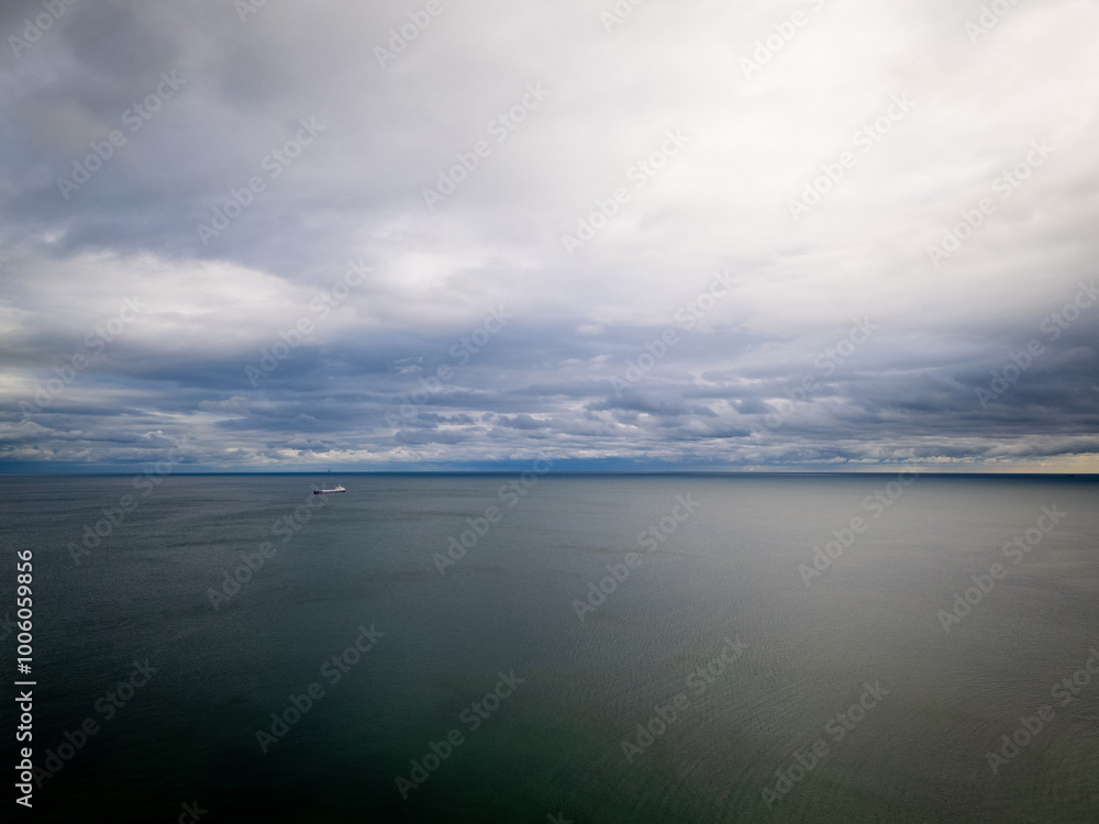 A panoramic view of a vast ocean under a dramatic, overcast sky. A distant ship on the horizon enhances the feeling of isolation and vastness. Ideal for seascape and maritime themes A panoramic view of a vast ocean under a dramatic, overcast sky. A distant ship on the horizon enhances the feeling of isolation and vastness. Ideal for seascape and maritime themes