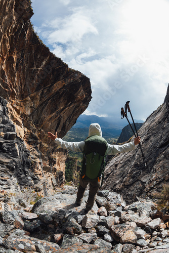 Backpacking woman climbing up on steep cliff edge at high altitude mountains top