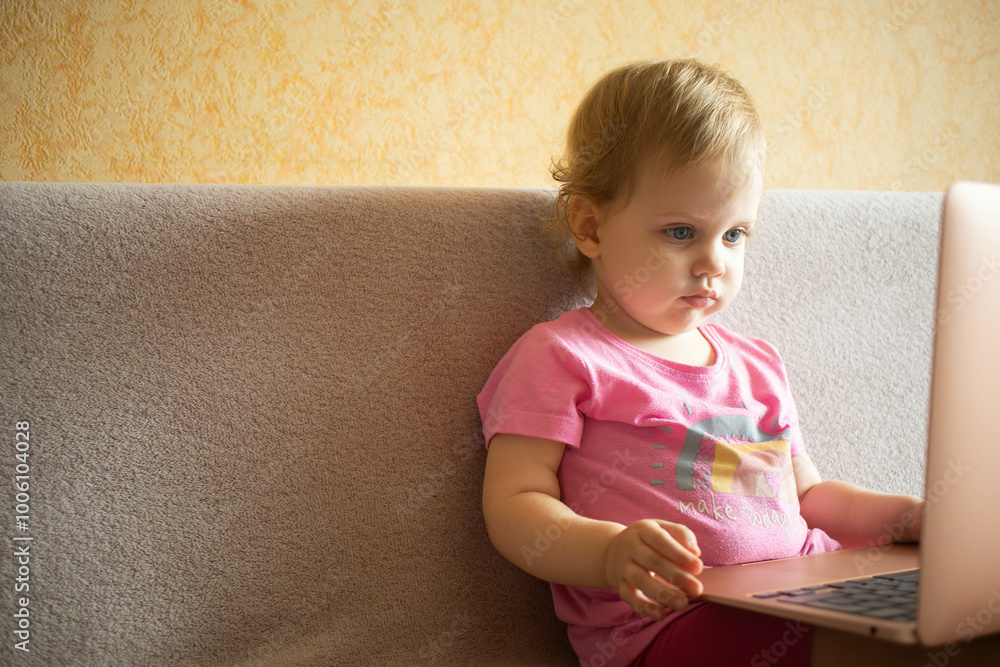 Cute girl sitting on bed watching something on laptop. Children's screen time. Cute girl sitting on bed watching something on laptop. Children's screen time.