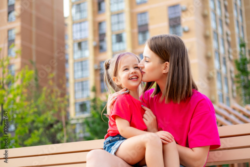 a child and his mother are talking on a park bench in the summer, having fun together, a happy childhood, mom and daughter