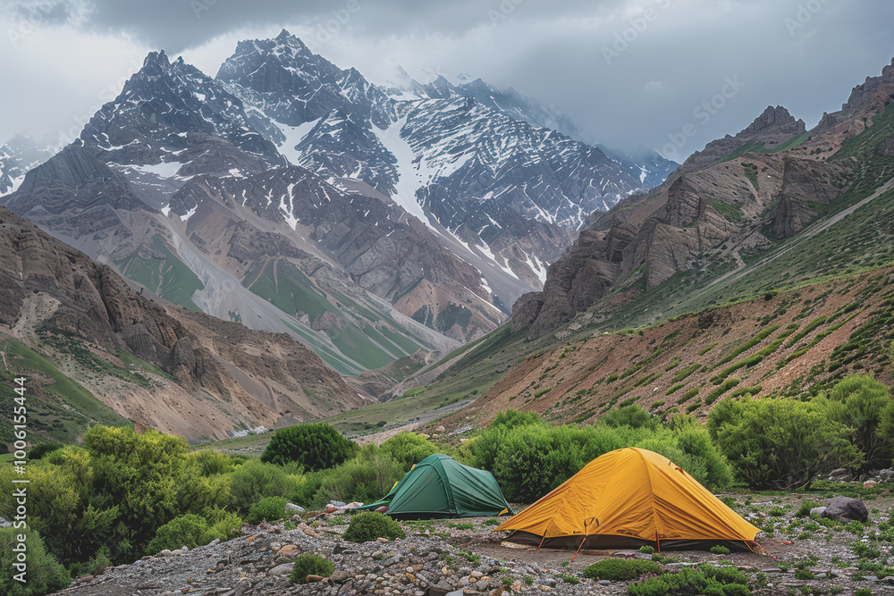 A campsite with two tents, one green and one yellow, set up in a mountainous area. A campsite with two tents, one green and one yellow, set up in a mountainous area.