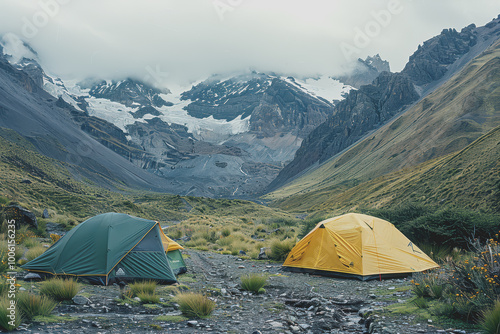 A campsite with two tents, one green and one yellow, set up in a mountainous area.