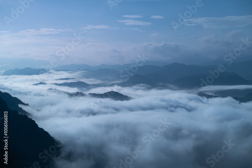 A breathtaking panoramic view of a sea of clouds below a crescent moon and a starry night sky. The silhouette of distant mountains adds depth and drama to this serene landscape. Xindian, Taiwan.