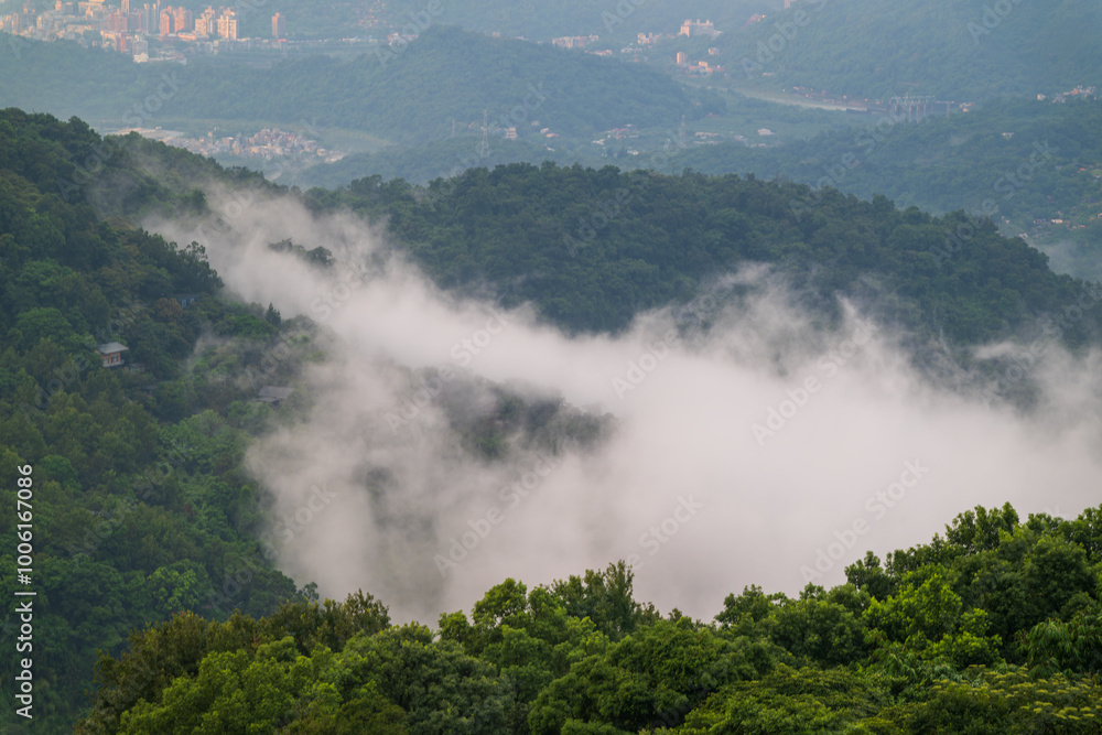 A breathtaking view of a lush green valley shrouded in mist. The clouds create a soft, ethereal atmosphere, while the distant mountains provide a dramatic backdrop. Xindian, Taiwan. A breathtaking view of a lush green valley shrouded in mist. The clouds create a soft, ethereal atmosphere, while the distant mountains provide a dramatic backdrop. Xindian, Taiwan.