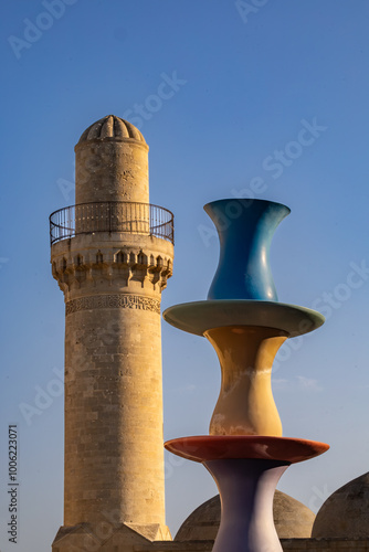 Baku, Azerbaijan A minaret at the Palace of the Shirvanshahs,  a 15th-century palace,  in the Old City and a sculture of tea cups. photo