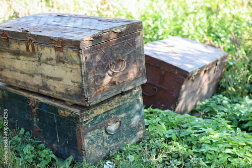 Three old wood chests closed outdoor on green grass.