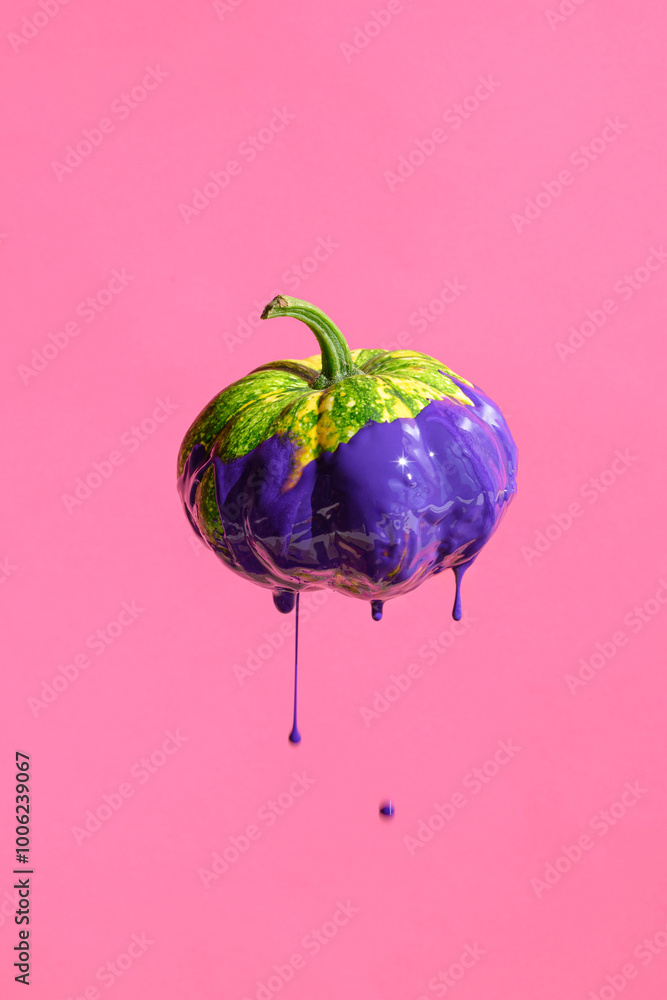 Obraz premium Decorative Autumn pumpkin with purple paint drips on pink background. Creative composition is perfect for fall, Halloween, or artistic-themed projects.