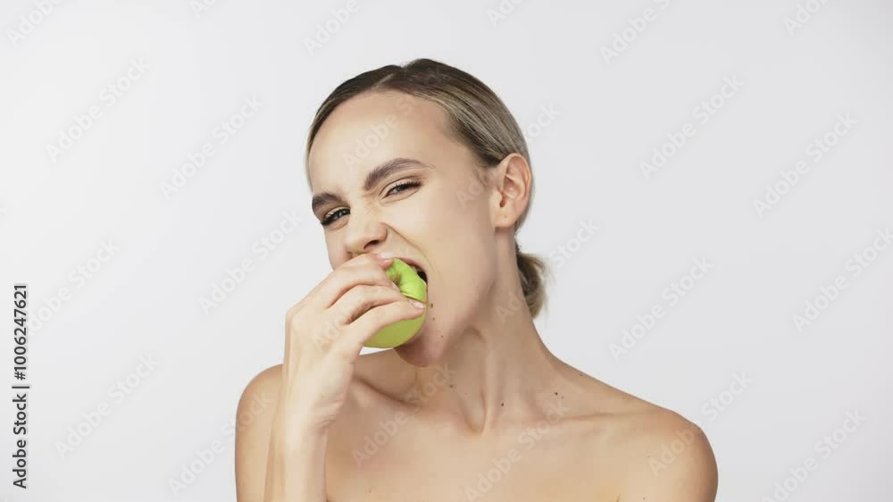 A young woman smiles while holding a green apple against a clean white background. This snack reflects her active lifestyle and commitment to wellness. A young woman smiles while holding a green apple against a clean white background. This snack reflects her active lifestyle and commitment to wellness.