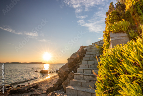 View through rocks on a sandy beach into the sunset. Landscape shot with a view to the horizon over the wide sea on the coast of Ouranoupoli, Thessaloniki, Central Macedonia, Greece photo