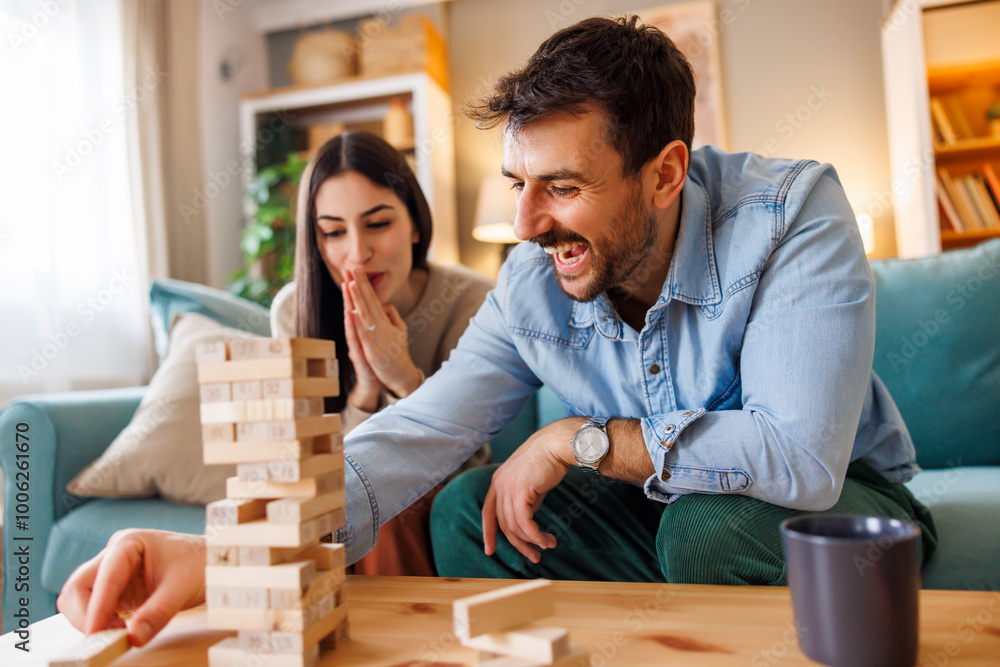 Boyfriend and girlfriend having fun playing wooden block stacking balance game Boyfriend and girlfriend having fun playing wooden block stacking balance game