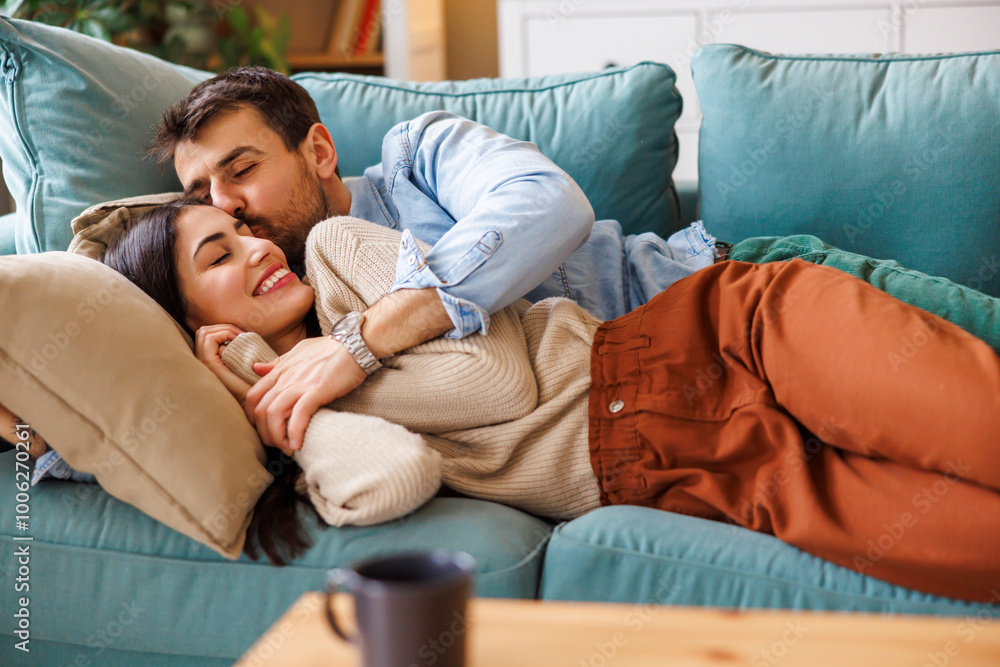 Obraz premium Couple cuddling and kissing while relaxing at home