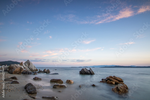 View through rocks on a sandy beach into the sunset. Landscape shot with a view to the horizon over the wide sea on the coast of Ouranoupoli, Thessaloniki, Central Macedonia, Greece photo