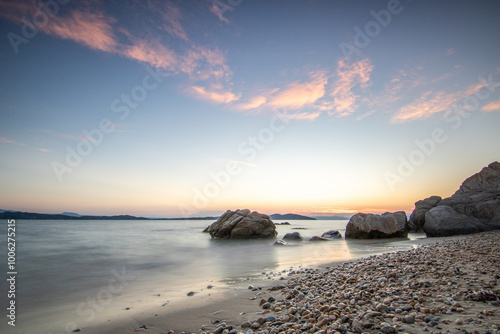 View through rocks on a sandy beach into the sunset. Landscape shot with a view to the horizon over the wide sea on the coast of Ouranoupoli, Thessaloniki, Central Macedonia, Greece photo