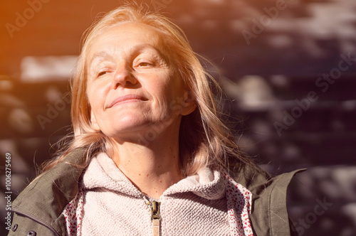 An elderly smiley wooman feels happy, walks in a park outdoors in the rays of a sun. photo