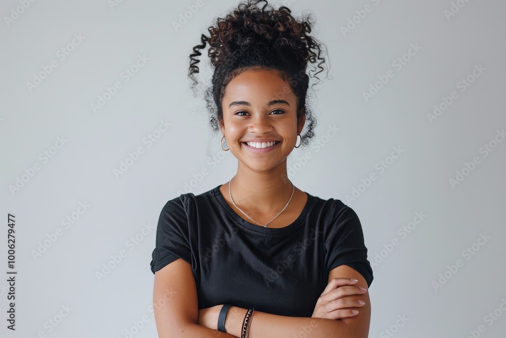 Fototapeta premium Portrait of a young woman with a genuine smile and arms folded, against a white background , background blur