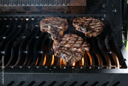 Three steaks cooking on a barbque