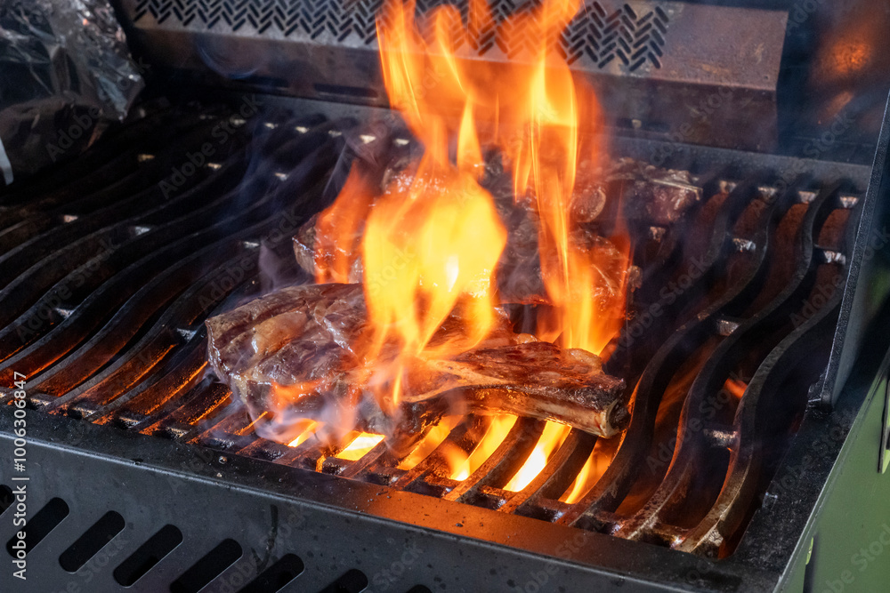 A steak broiling with flame on a barbecue