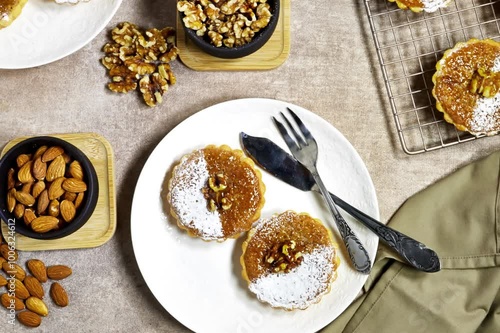 Delicious homemade chocolate tarts named Amandines in frensh surrounded by walnuts and almonds being presented on a table photo